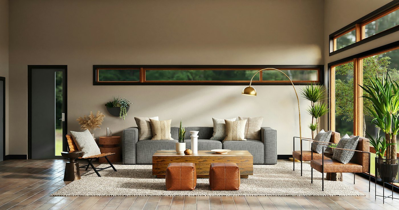A grey sofa, a wood coffee table, two leather stools, and tall windows onto trees